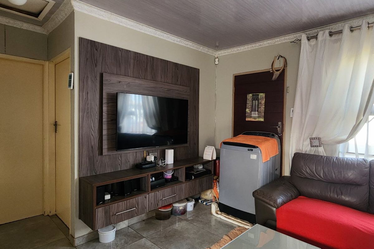 Living room featuring a built-in media unit, tiled flooring, and decorative ceiling coving, providing a functional space with potential for cosmetic updates.