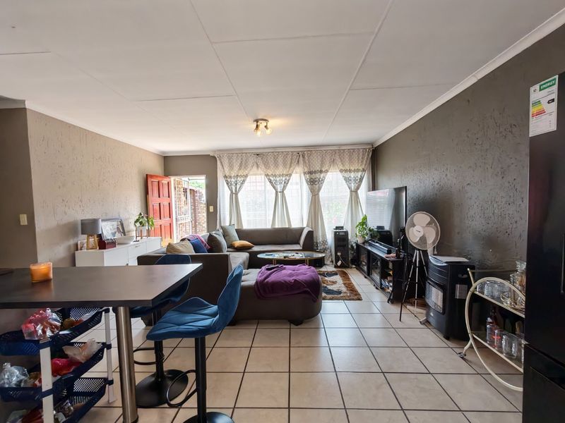 Open plan living area featuring tiled flooring and textured wall finishes, providing a functional space with direct access to the exterior.