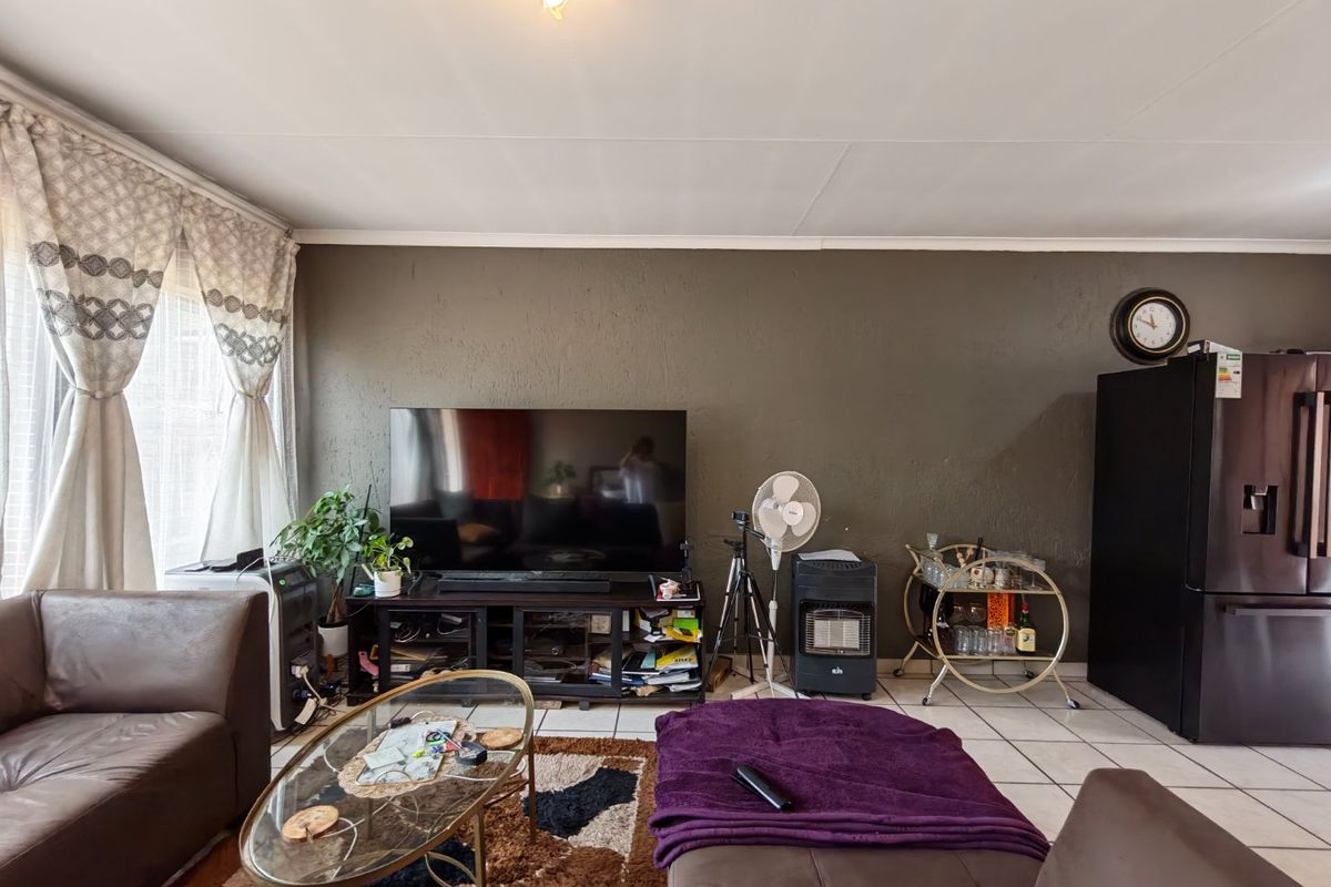 A living room featuring tiled flooring and a neutral wall finish, providing a functional space for relaxation.