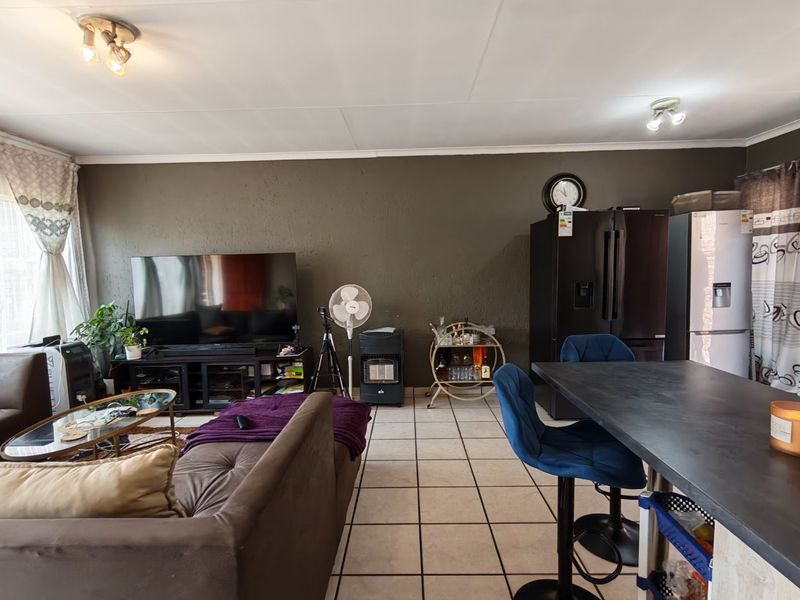 An open-plan living and dining area featuring tiled flooring and neutral wall finishes, providing a functional space for daily living.