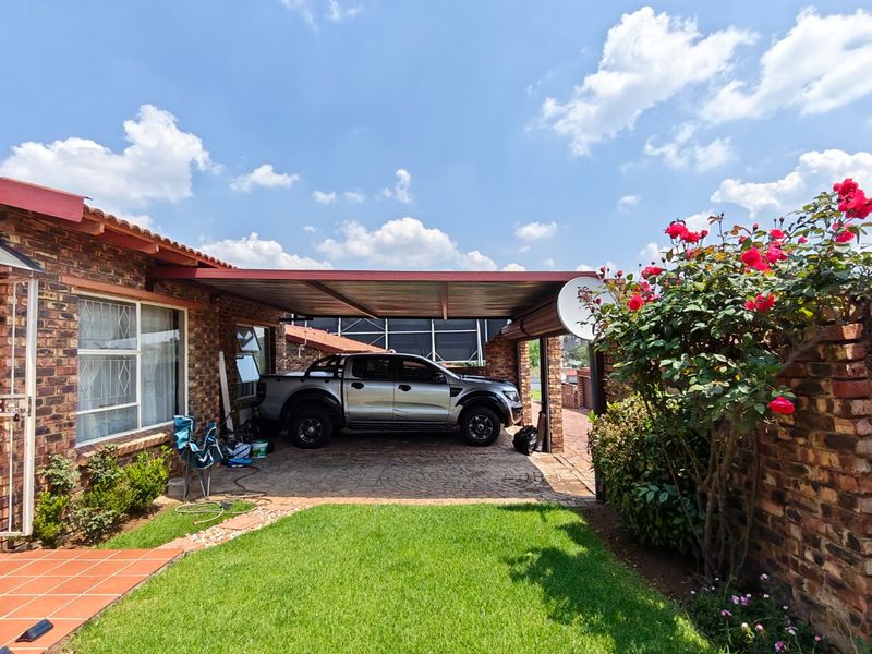 Front exterior view of the townhouse featuring a face brick facade, a covered carport, and a well-maintained garden area.