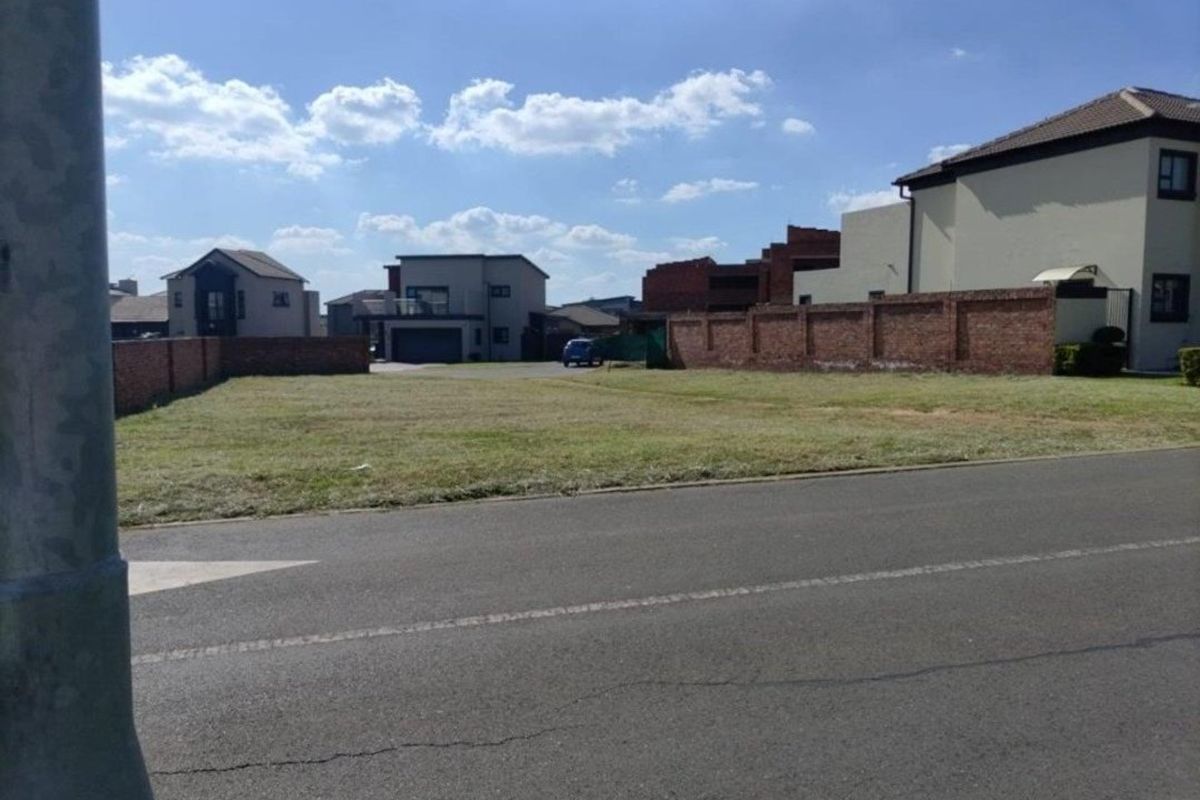 A vacant residential plot situated in a developed neighborhood, featuring established brick boundary walls and direct street access.