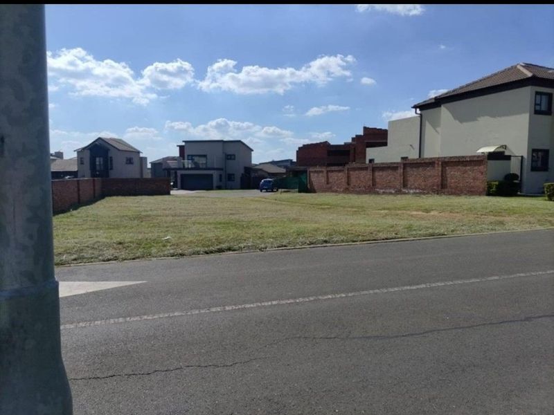 A vacant residential plot situated in a developed neighborhood, featuring established brick boundary walls and direct street access.