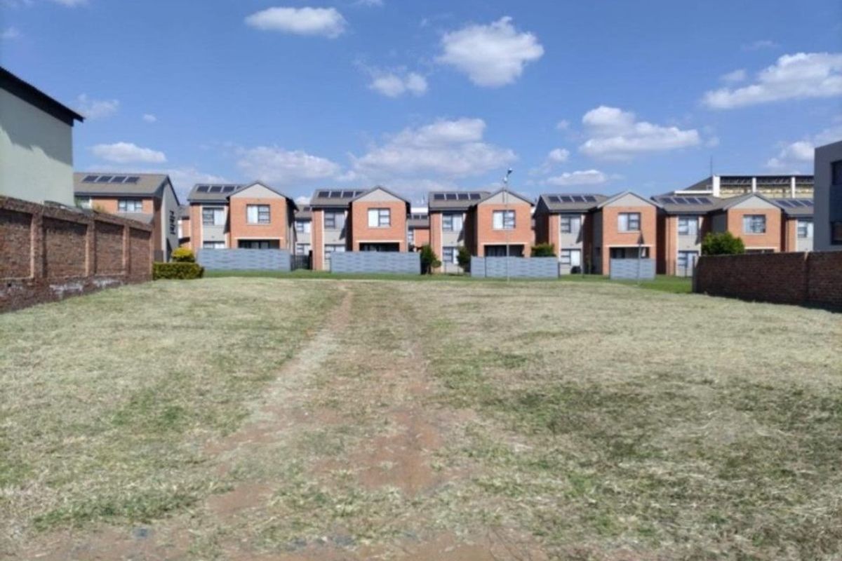 A vacant residential plot of land enclosed by brick boundary walls, situated in a developed residential estate.
