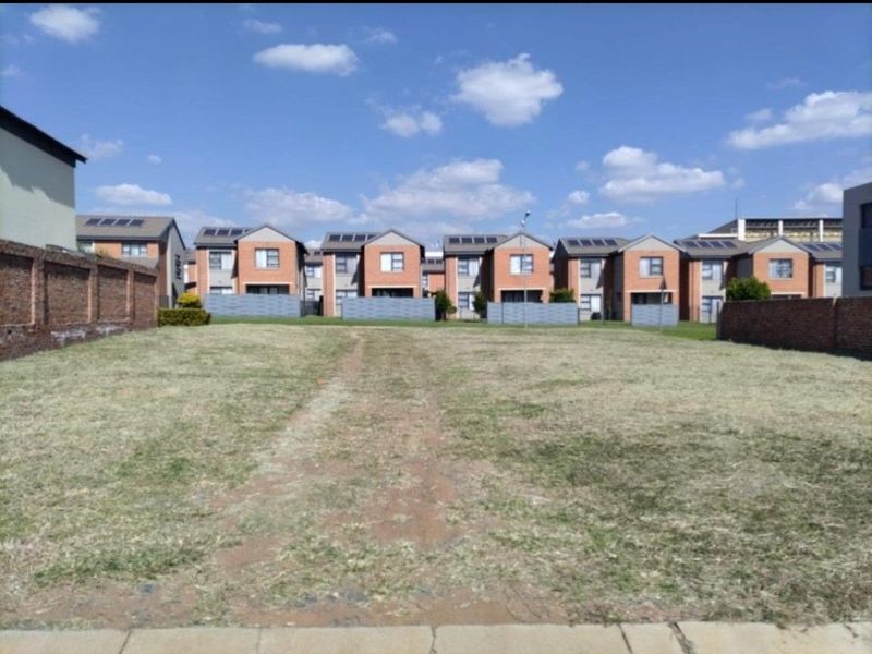 A vacant residential plot of land enclosed by brick boundary walls, situated in a developed residential estate.