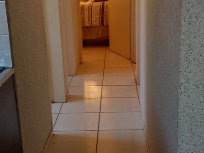 A functional hallway featuring tiled flooring and textured wall finishes, providing access to adjacent rooms.