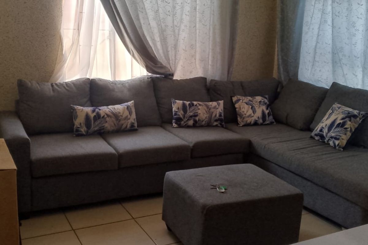A living room area featuring tiled flooring and window treatments, providing a functional space for relaxation.