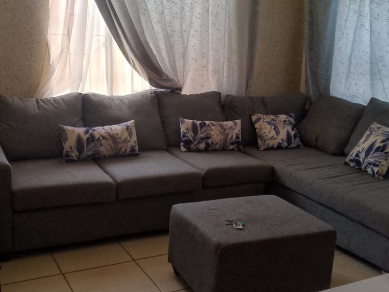 A living room area featuring tiled flooring and window treatments, providing a functional space for relaxation.