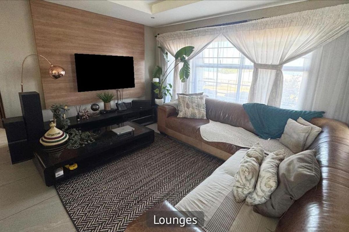 A comfortable living room featuring a wood-look feature wall, recessed ceiling lighting, and large windows with natural light.