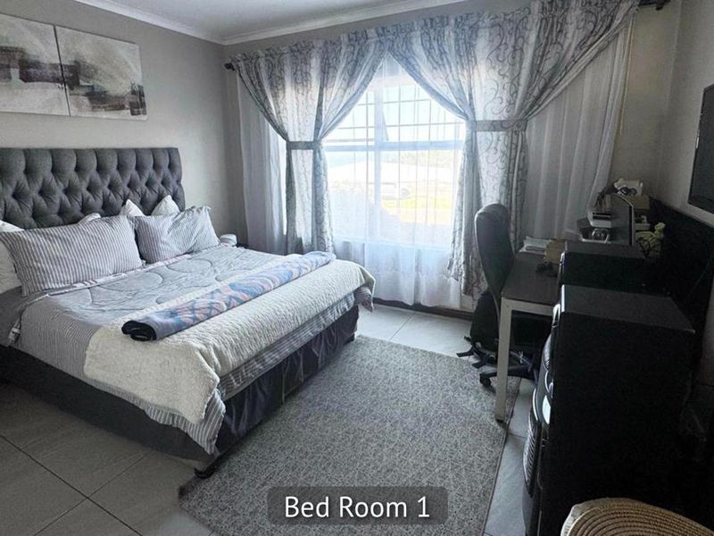 A functional bedroom featuring tiled flooring and a window fitted with security bars, providing natural light.