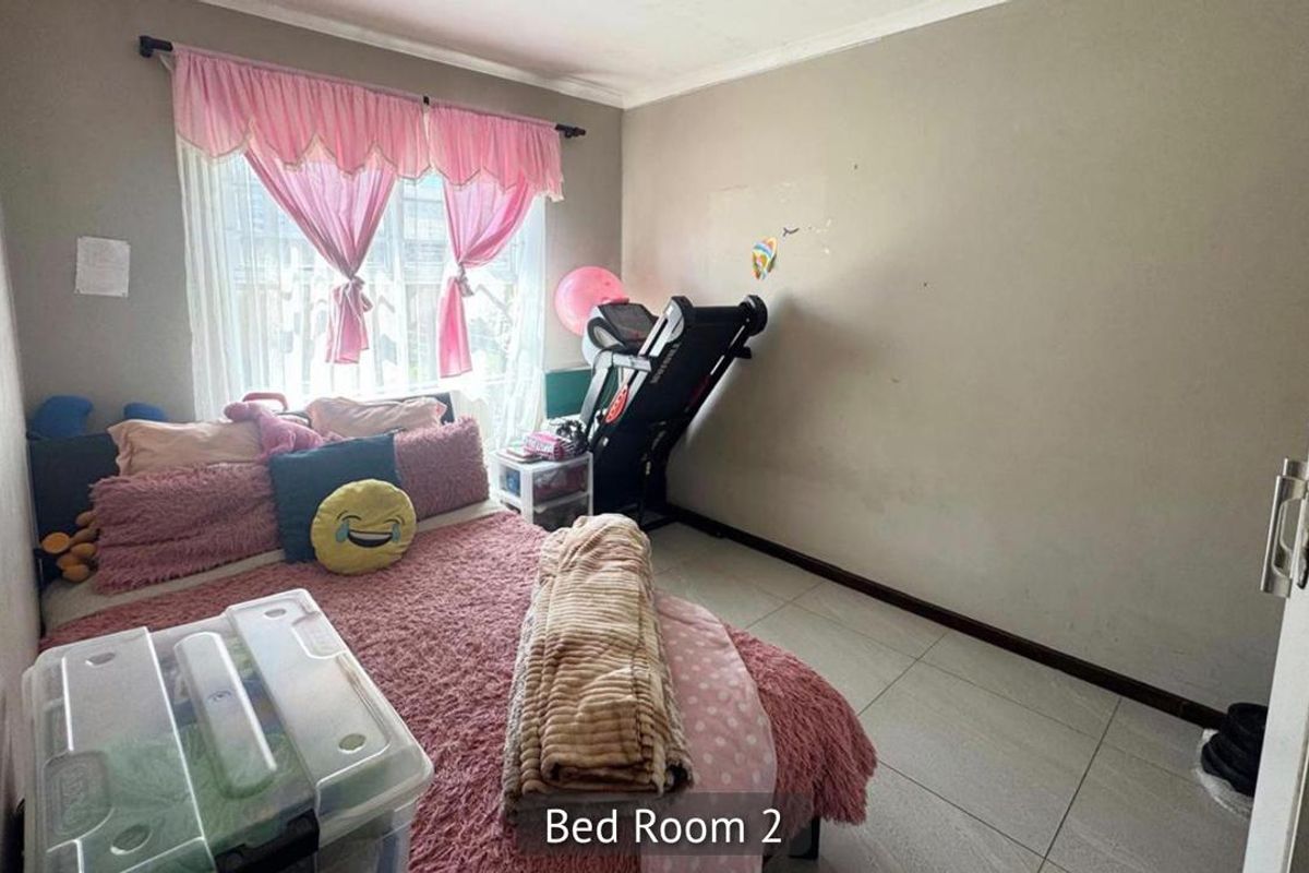 A bedroom featuring tiled flooring and a window with a curtain rod, currently showing signs of wear on the wall surfaces.