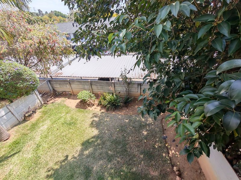 A private garden area featuring a lawn, established trees, and a precast concrete boundary wall.