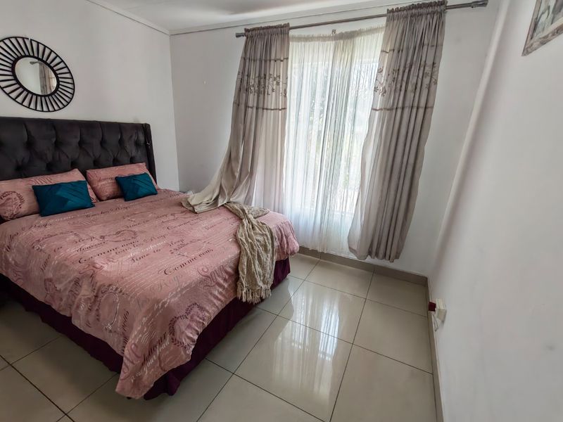 A bedroom featuring tiled flooring and a large window with curtain fixtures.
