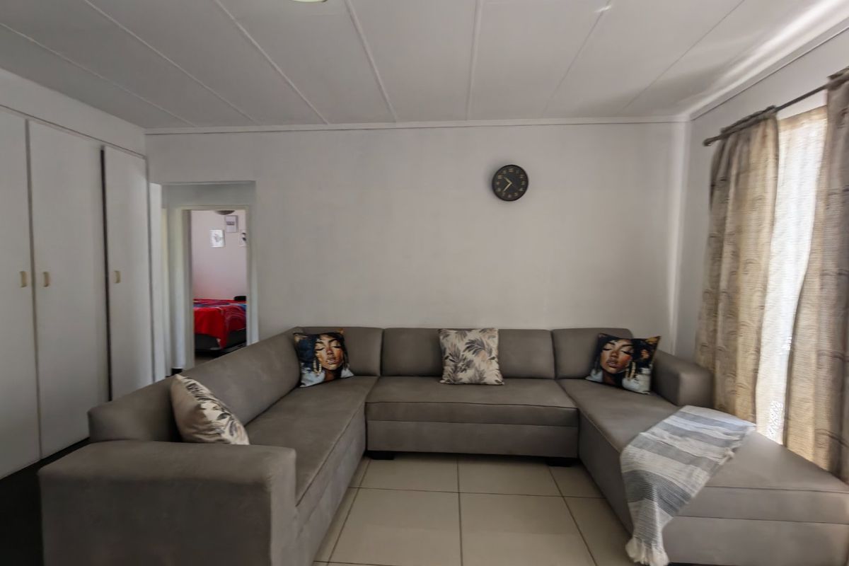 A living room featuring tiled flooring, built-in cupboards, and ceiling panels, offering a functional and neutral space for relaxation.