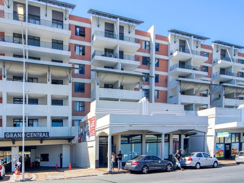 Exterior view of the Grand Central apartment complex featuring a multi-story facade with balconies and ground-level commercial retail spaces.