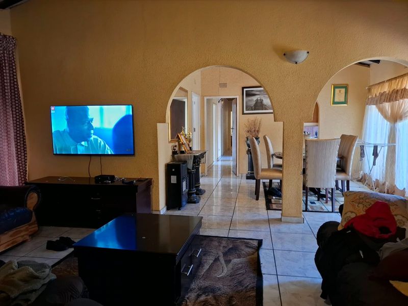 Open plan living and dining area featuring arched architectural details, tiled flooring, and a neutral wall finish.