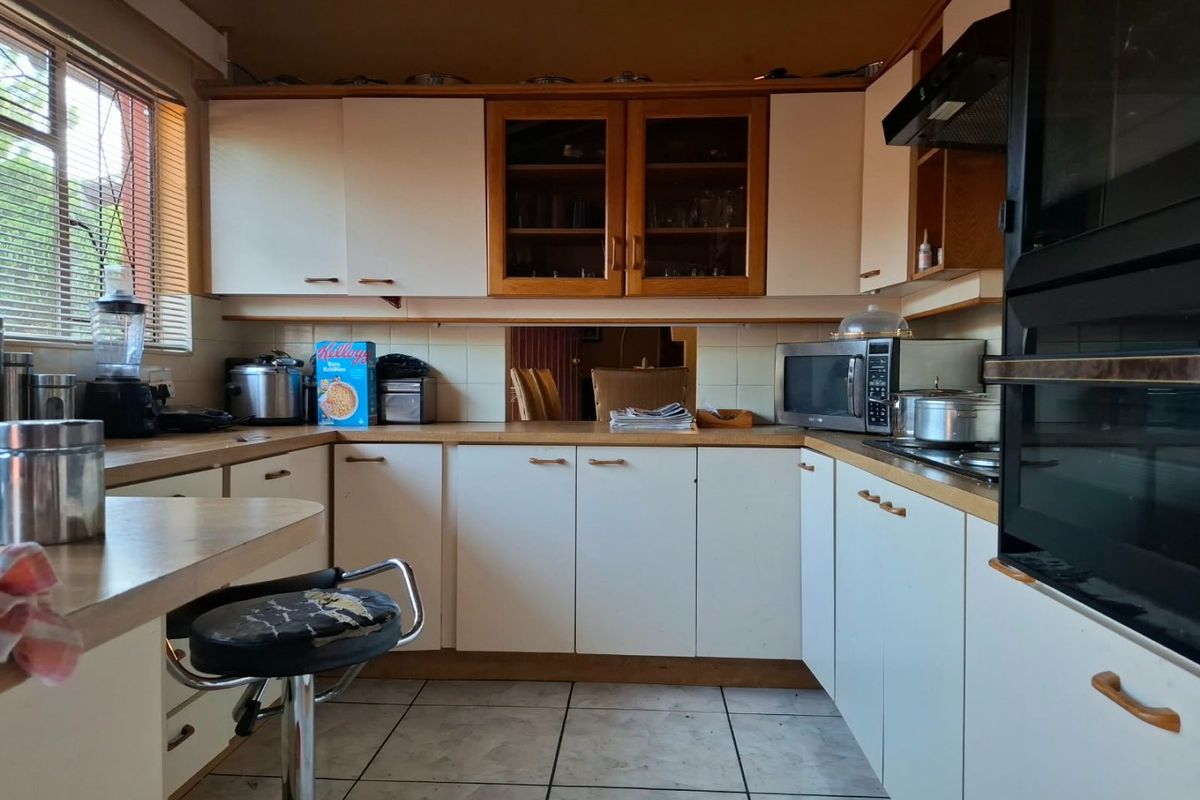 A functional kitchen featuring white cabinetry, laminate countertops, and tiled flooring. The space offers a classic layout with built-in oven and extractor fan.
