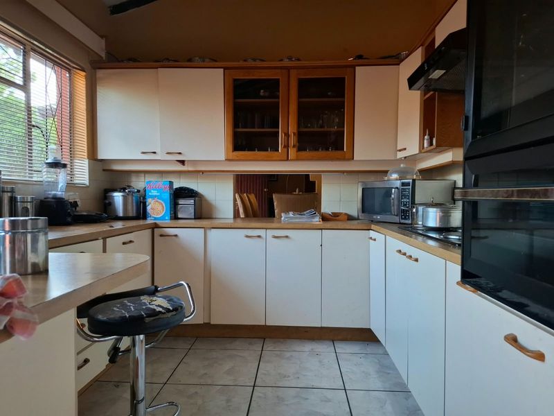 A functional kitchen featuring white cabinetry, laminate countertops, and tiled flooring. The space offers a classic layout with built-in oven and extractor fan.