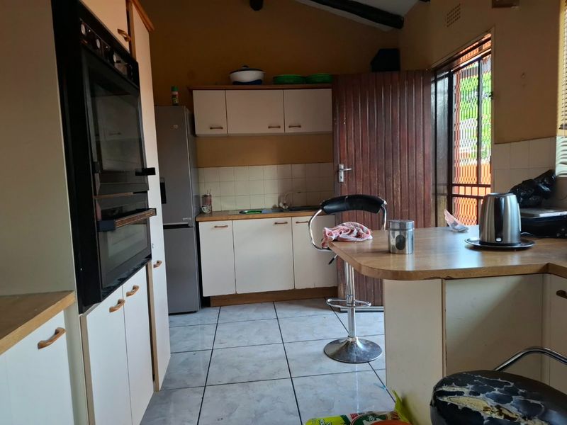 A functional kitchen featuring built-in cabinetry, an integrated oven, and tiled flooring, offering a practical layout with potential for modern updates.