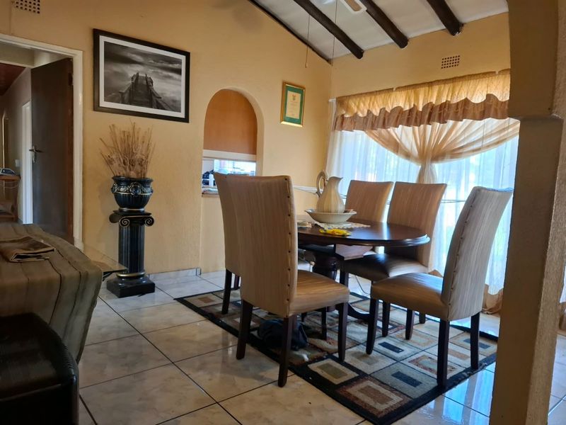 Dining room featuring tiled flooring, exposed timber ceiling beams, and an arched wall niche, providing a functional space for family meals.