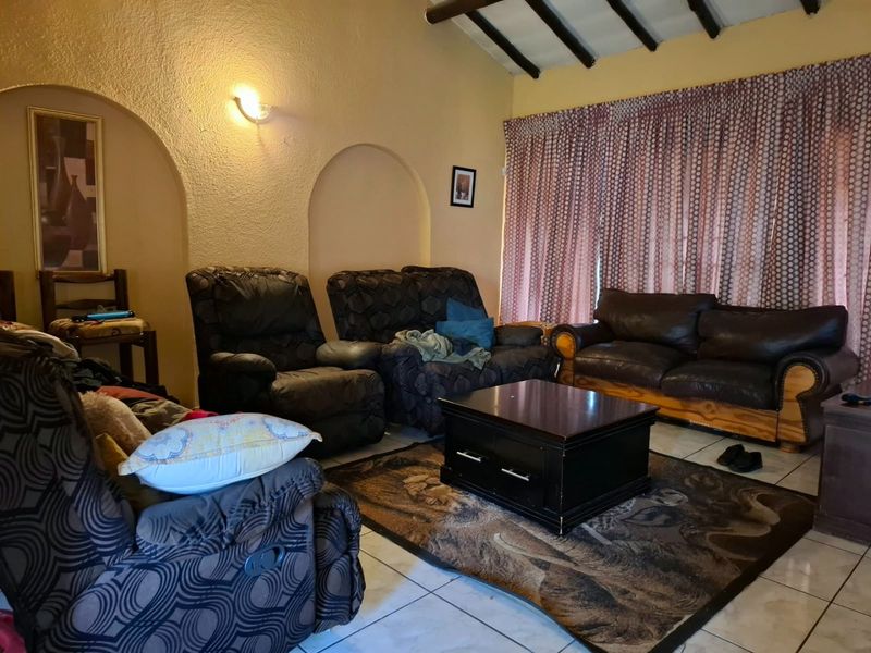 A living room featuring exposed timber ceiling beams, arched wall niches, and tiled flooring, offering a cozy and traditional atmosphere.