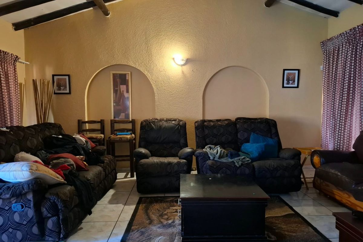 A living room featuring exposed timber ceiling beams, tiled flooring, and decorative arched wall niches, providing a rustic architectural foundation.