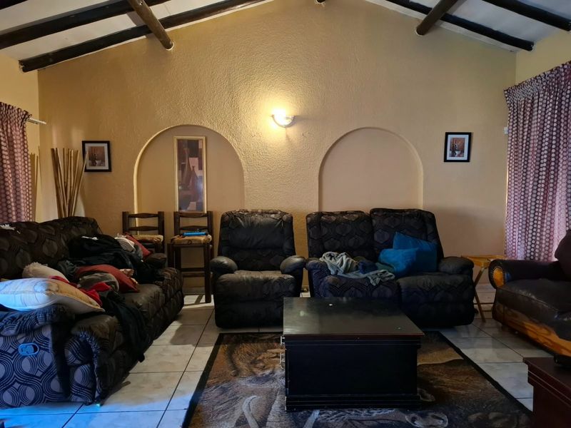 A living room featuring exposed timber ceiling beams, tiled flooring, and decorative arched wall niches, providing a rustic architectural foundation.