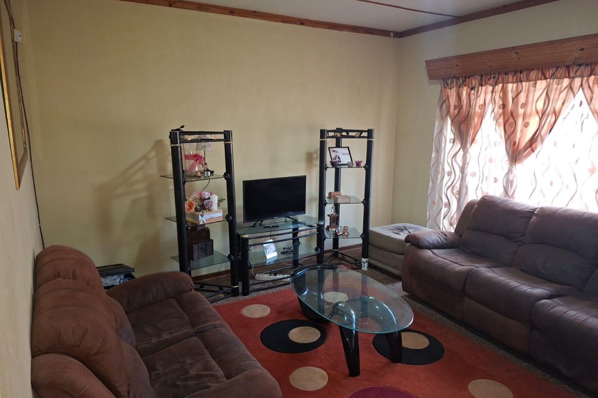 A living room featuring timber ceiling trim and a timber window pelmet, offering a dated aesthetic ready for modernization.