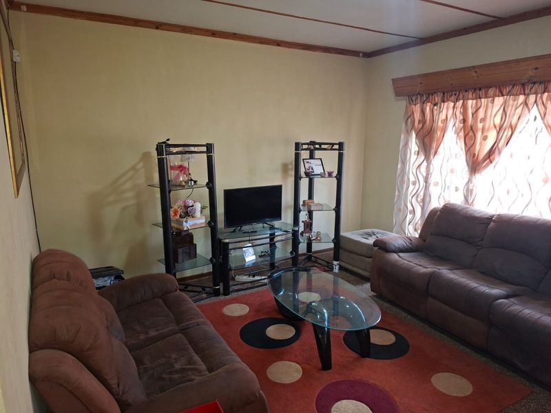 A living room featuring timber ceiling trim and a timber window pelmet, offering a dated aesthetic ready for modernization.