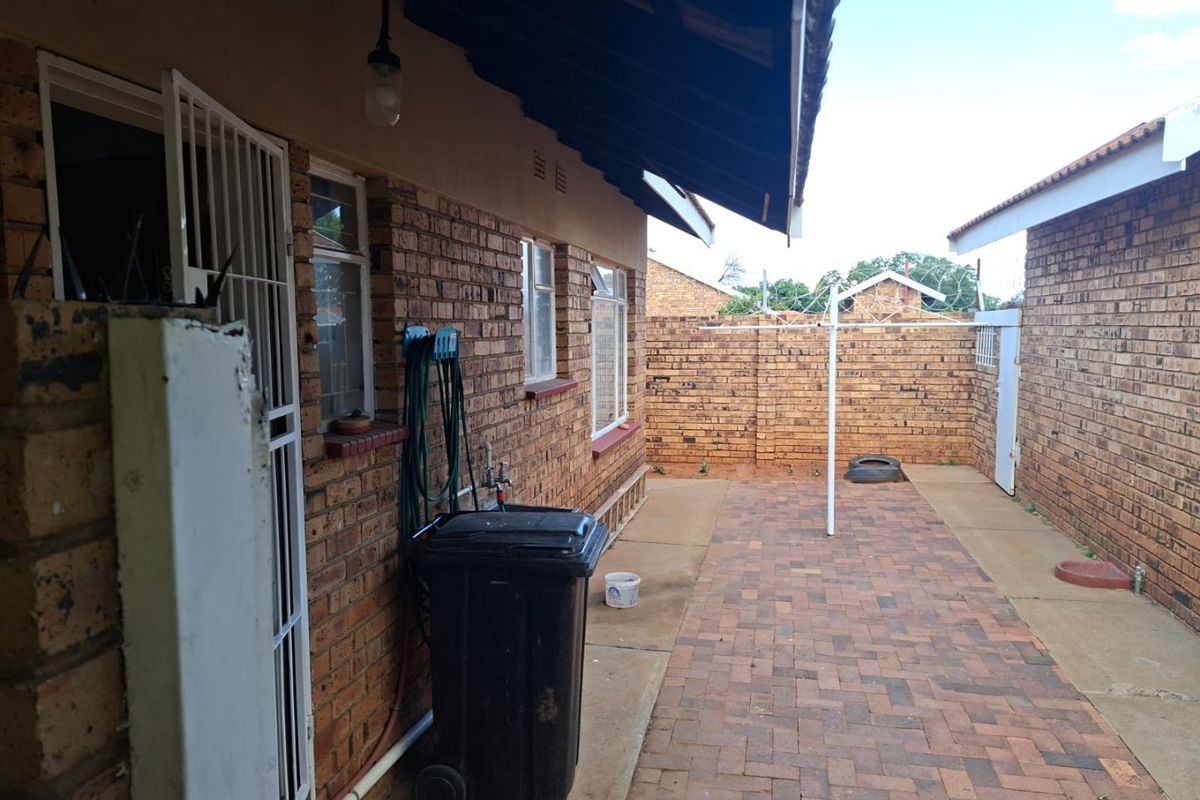 A private rear courtyard featuring face brick walls, paved flooring, and secure perimeter fencing, providing a functional outdoor utility space.