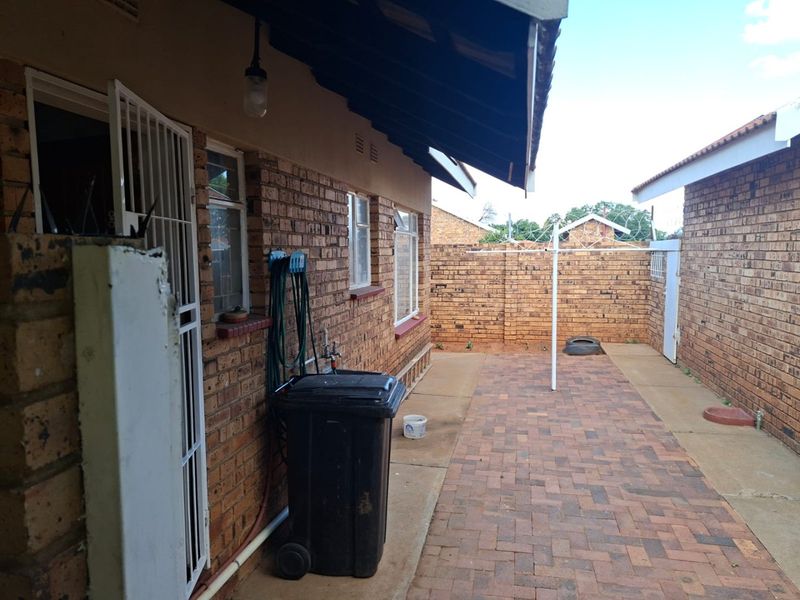 A private rear courtyard featuring face brick walls, paved flooring, and secure perimeter fencing, providing a functional outdoor utility space.