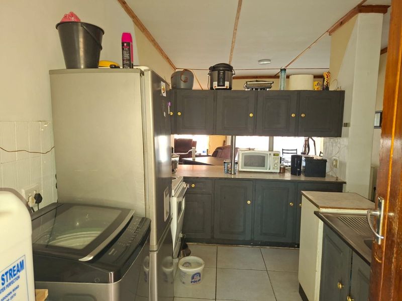 A functional kitchen featuring dark cabinetry, tiled flooring, and integrated appliances, offering potential for modernization and aesthetic improvement.