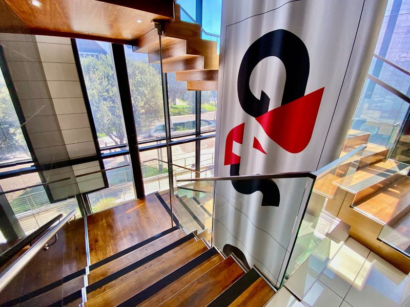 Modern commercial entrance featuring a striking timber staircase with glass balustrades and expansive floor-to-ceiling windows providing ample natural light.