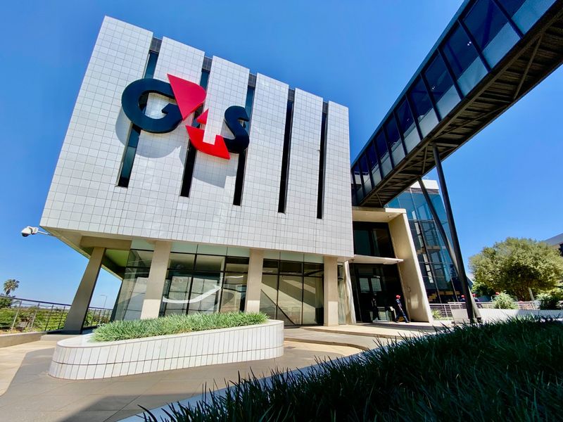 Modern commercial building exterior featuring a tiled facade, glass curtain wall, and an elevated pedestrian bridge connecting structures.