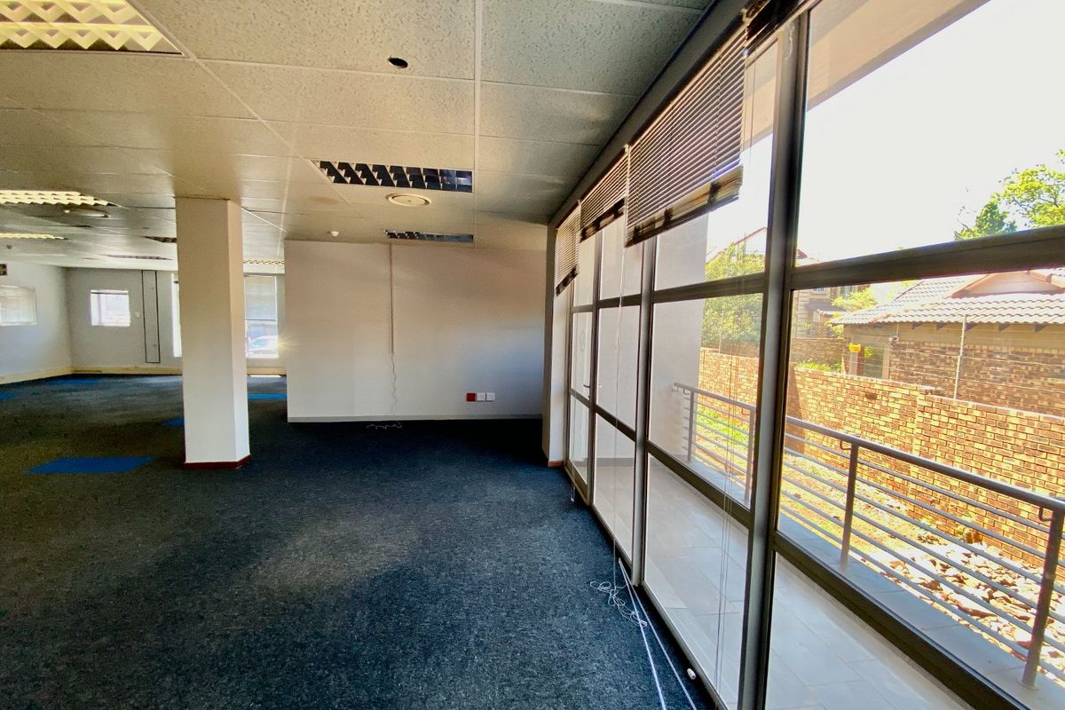 Spacious open-plan office area featuring large windows, suspended ceilings with recessed lighting, and carpeted flooring, offering a bright and versatile workspace.