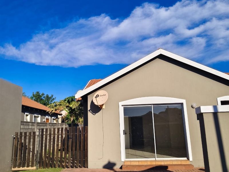 Rear view of the property featuring a paved patio area, sliding glass door access, and a private garden with wooden fencing.
