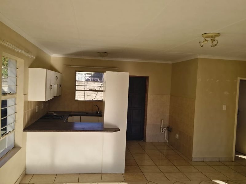 Open plan living and kitchen area featuring tiled flooring, built-in cabinetry, and a breakfast bar, offering a blank canvas for renovation.