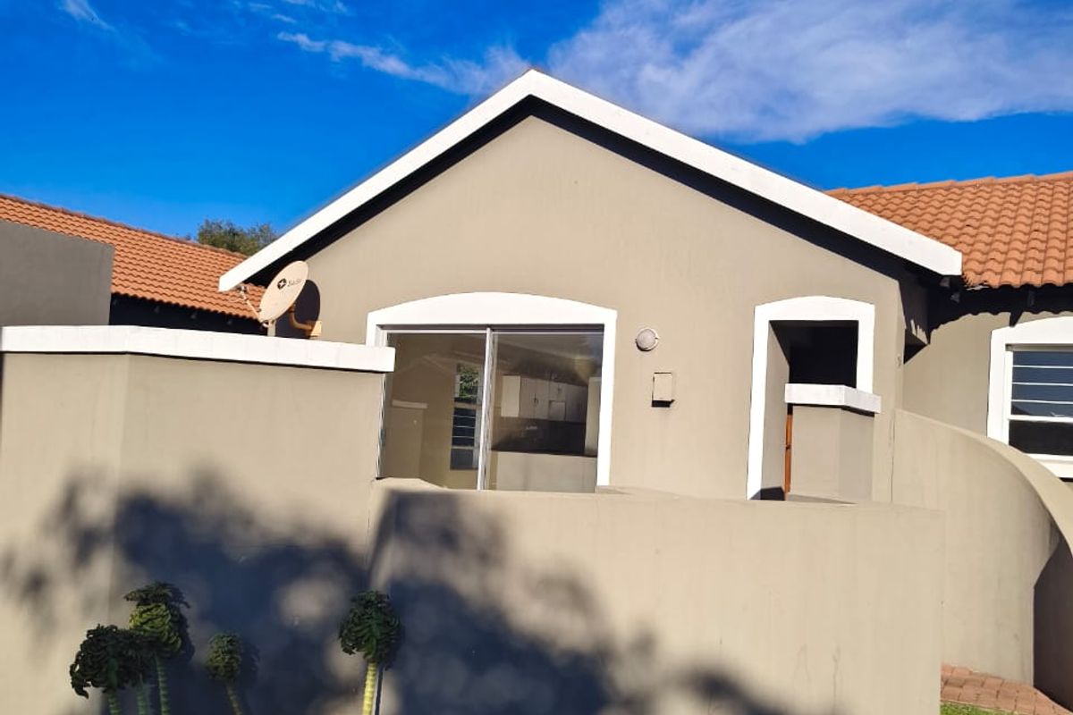 A view of the rear exterior of the house featuring a sliding glass door, tiled roof, and a surrounding boundary wall.