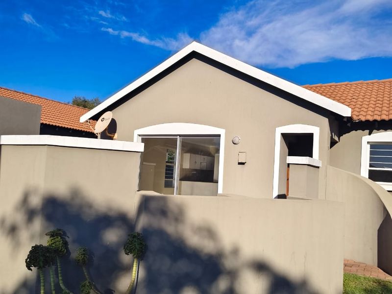 A view of the rear exterior of the house featuring a sliding glass door, tiled roof, and a surrounding boundary wall.
