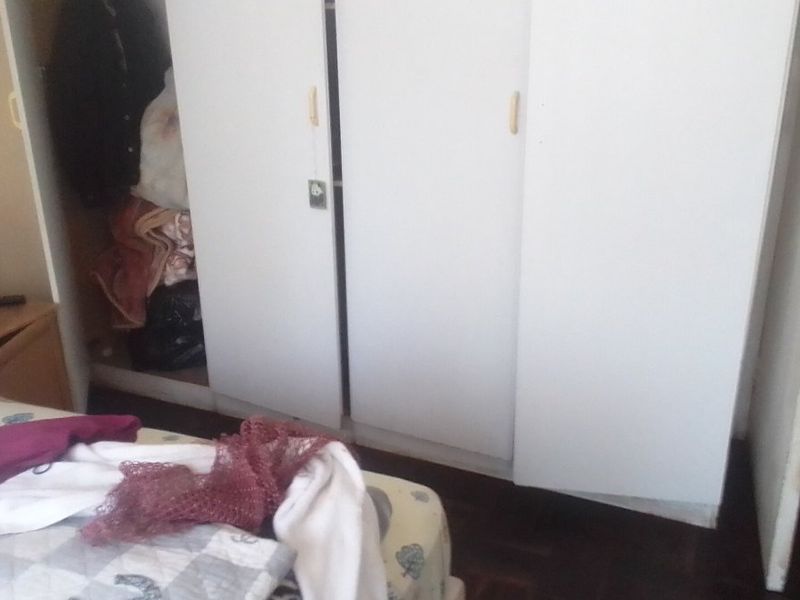A bedroom featuring a built-in wardrobe with white doors and dark wood-look flooring.