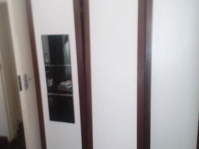 A bedroom interior featuring built-in cupboards with dark wood trim and a small integrated mirror panel.