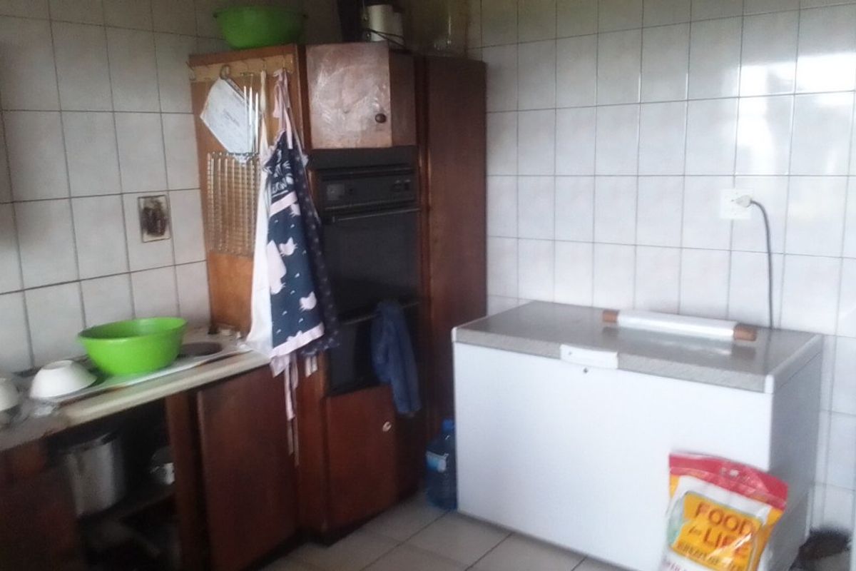 A dated kitchen area featuring built-in cabinetry, an integrated oven, and tiled wall splashbacks, offering potential for modernization and renovation.