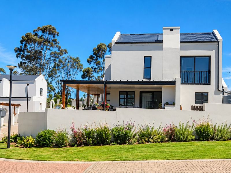 A modern double-story residential home featuring a covered patio, balcony, and clean architectural lines, set within a well-maintained estate environment.