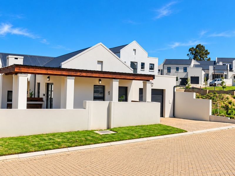 Modern residential property featuring a paved driveway, integrated garage, and a covered patio with a timber pergola structure.