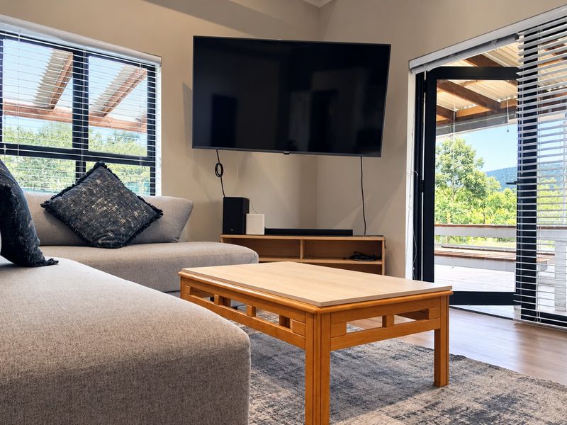 A bright living room featuring laminate flooring, large windows, and a sliding glass door providing access to an outdoor patio area.