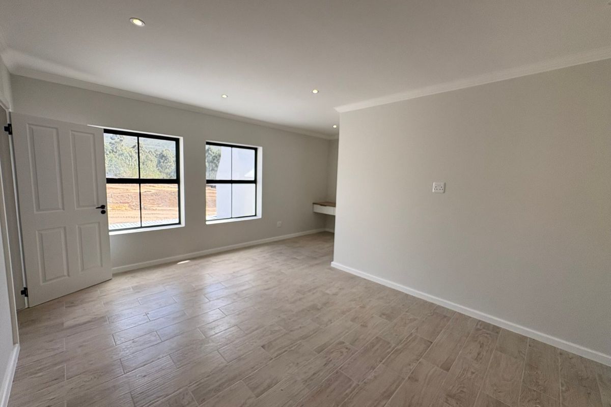 A bright, empty bedroom featuring modern tiled flooring, recessed downlights, and a built-in desk area, offering a clean and neutral canvas.