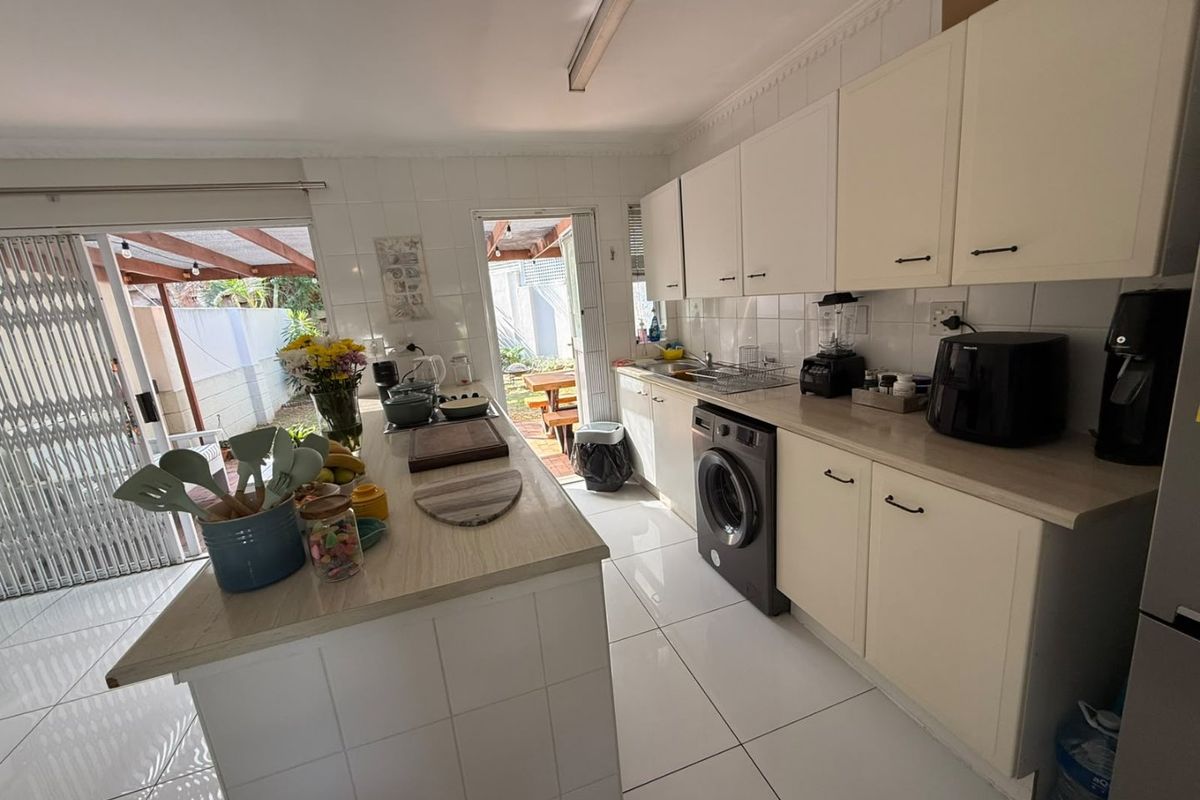 Functional kitchen featuring tiled flooring, ample built-in cabinetry, a central island, and direct access to the outdoor patio area.