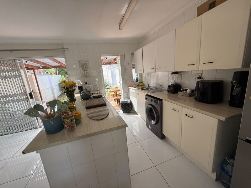 Functional kitchen featuring tiled flooring, ample built-in cabinetry, a central island, and direct access to the outdoor patio area.