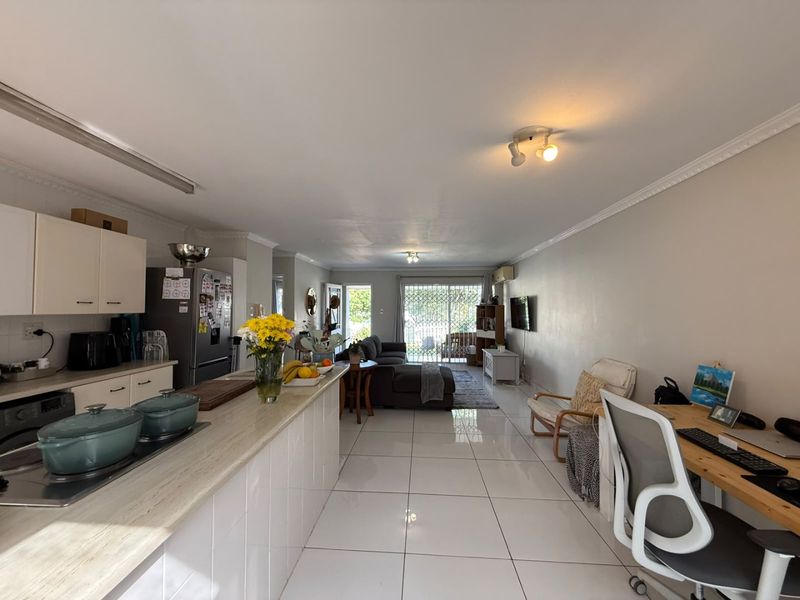 Spacious open-plan living area featuring a functional kitchen with stone countertops, tiled flooring throughout, and direct access to the outdoor patio area.