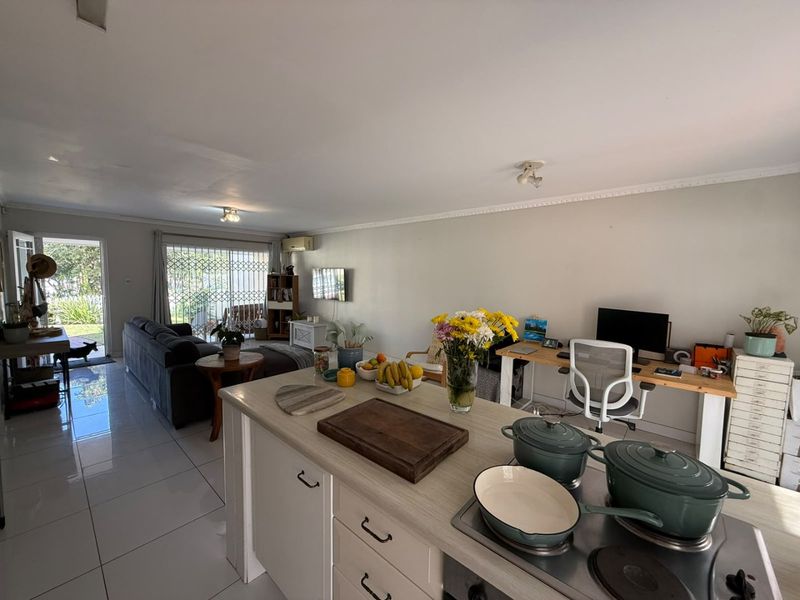 Spacious open-plan living area featuring a modern kitchen island with integrated hob, tiled flooring, and large sliding doors leading to the outdoor space.